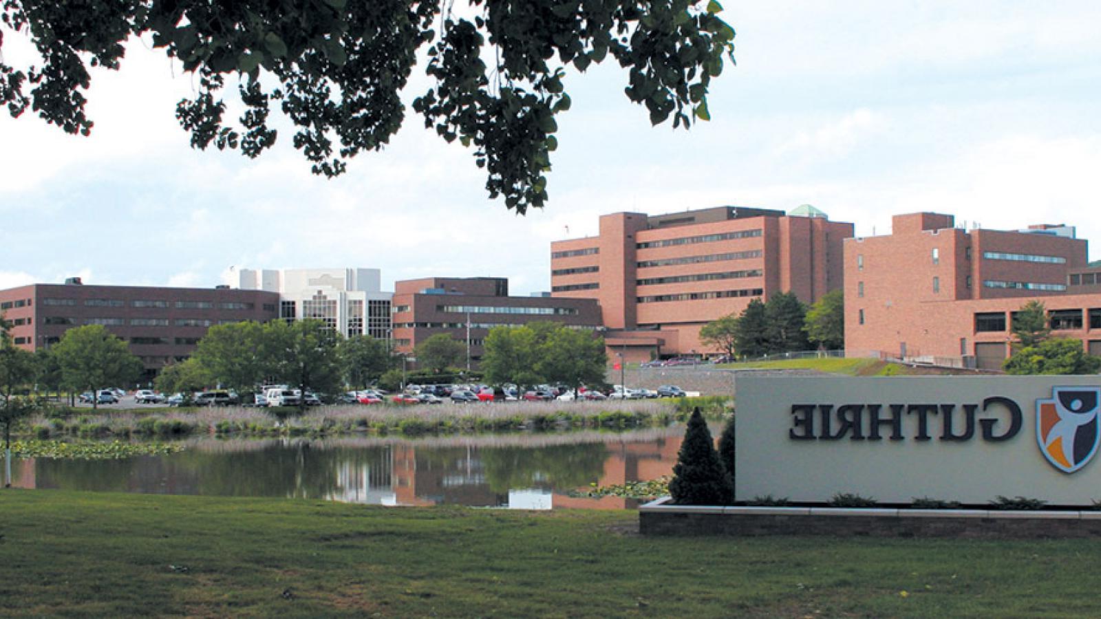 Guthrie sign with campus in the background 